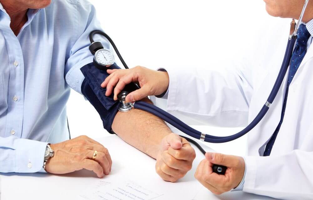Bác sĩ đang đo huyết áp động mạch cánh tay cho người bệnh bằng máy cơ và ống nghe chuẩn y khoa